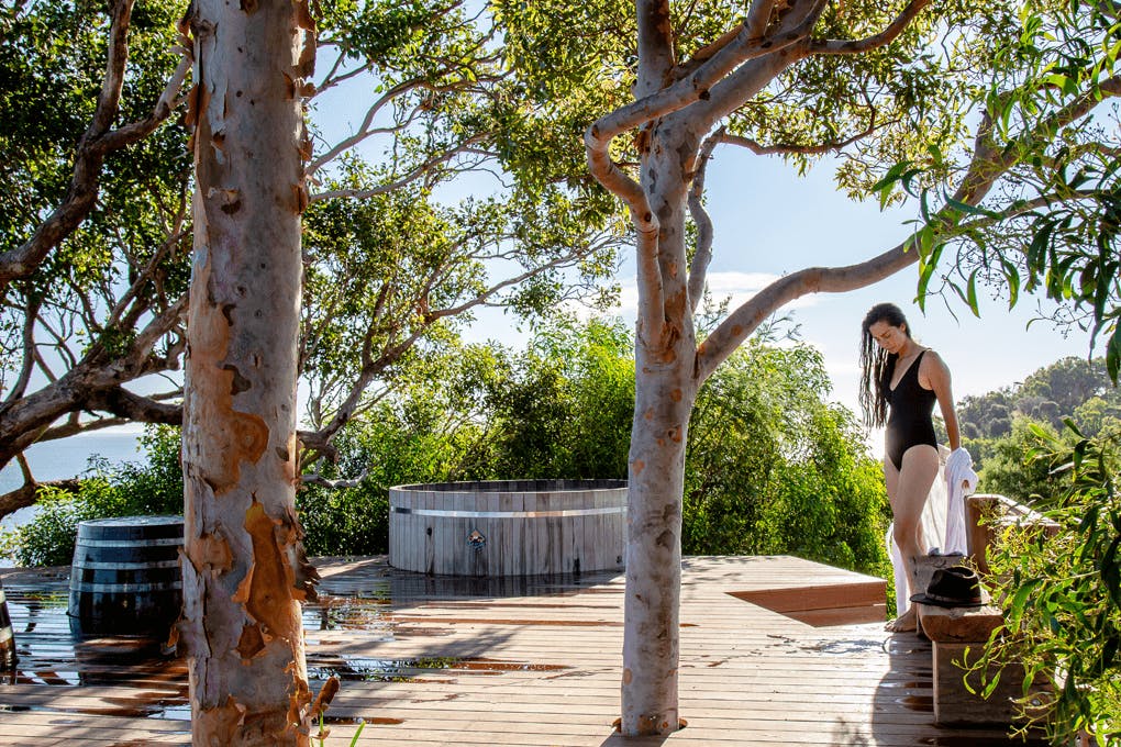 A person in a swimsuit in nature near a bathtub.